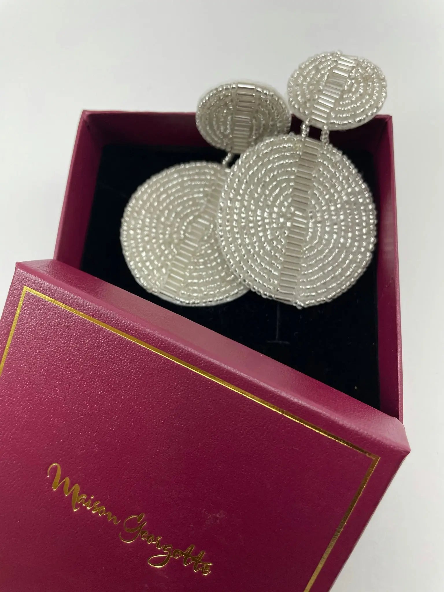 Luxury women's earrings, the Brenda Discus Earring, showcased in a pink box with white beading