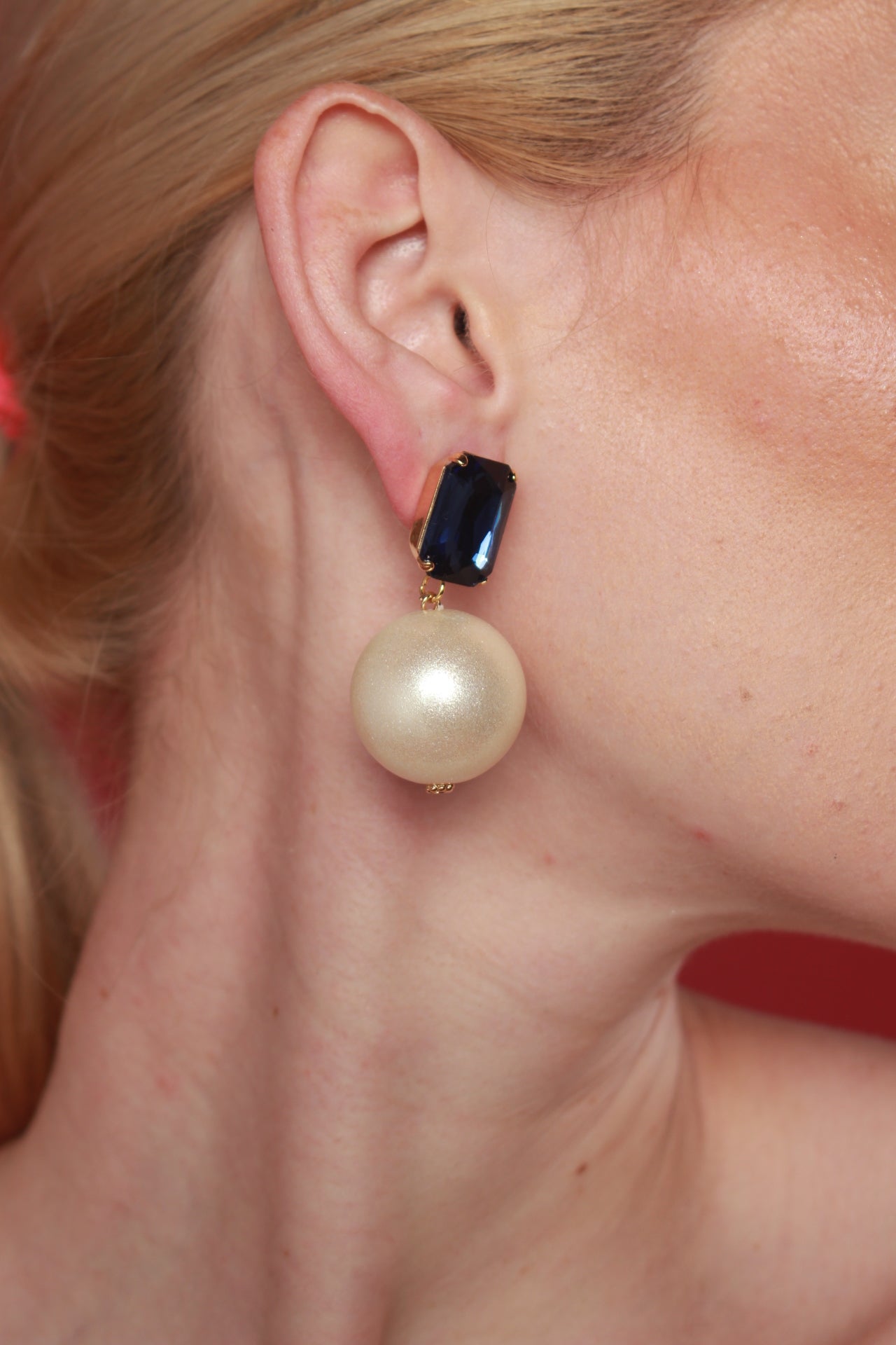 A woman elegantly displays Dana Teardrop earrings, crafted with pearls highlighting luxury women's earrings