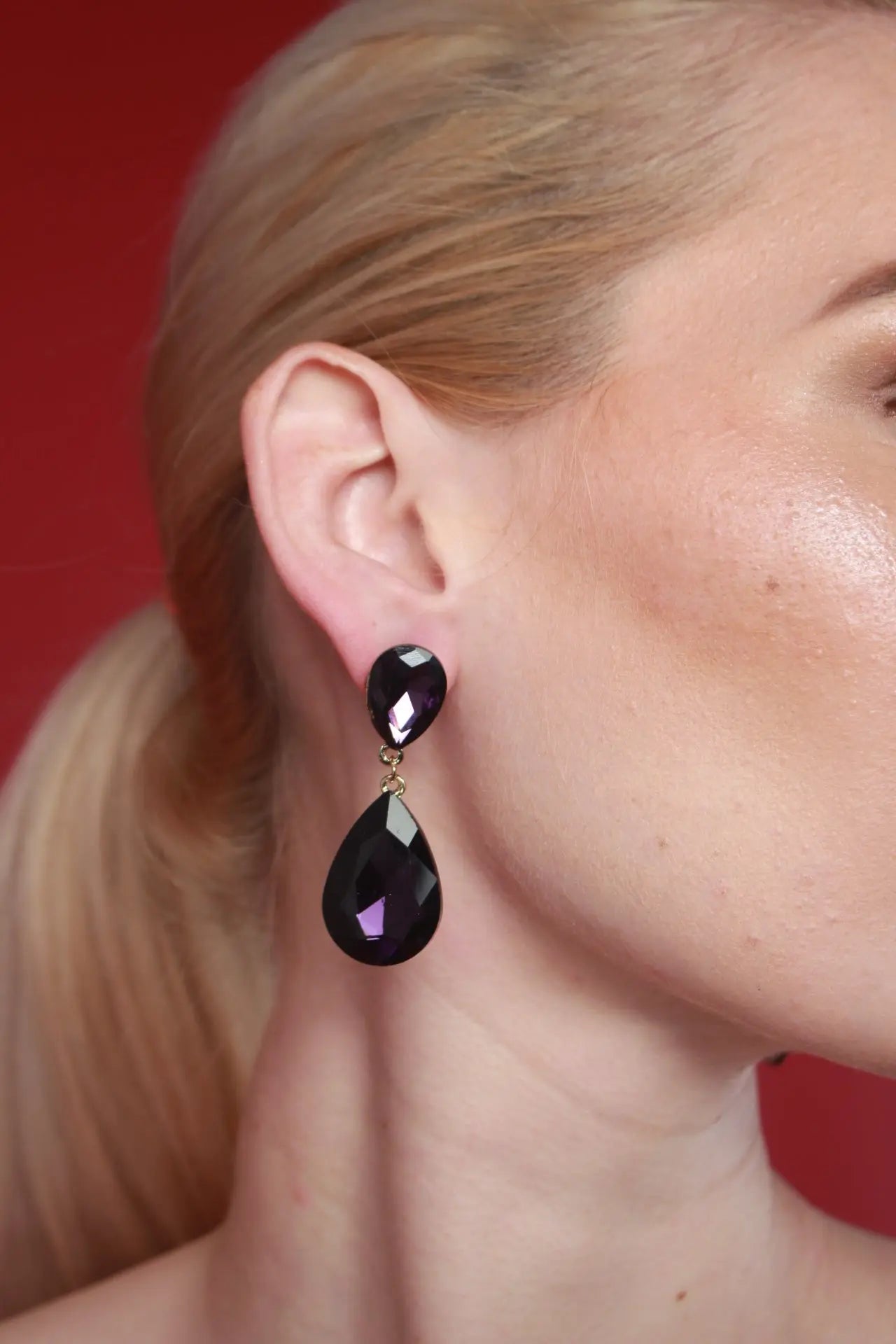 A woman in a white elegantly displays black Lori Teardrop Earrings, showcasing her luxury women's earrings