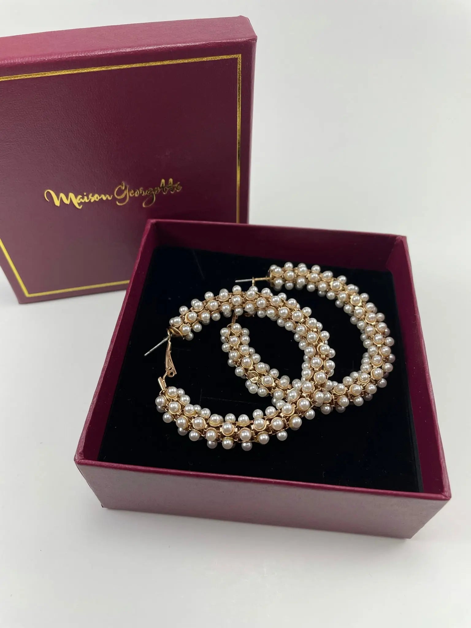 A pair of Stella Pearl Hoop earrings in a box, representing luxury women's earrings