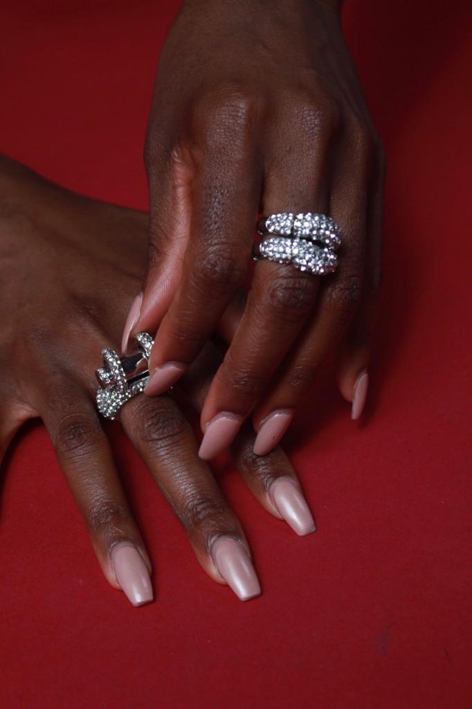 A woman displaying her hands with two luxurious women's rings, prominently featuring the stylish Leo Cocktail Ring