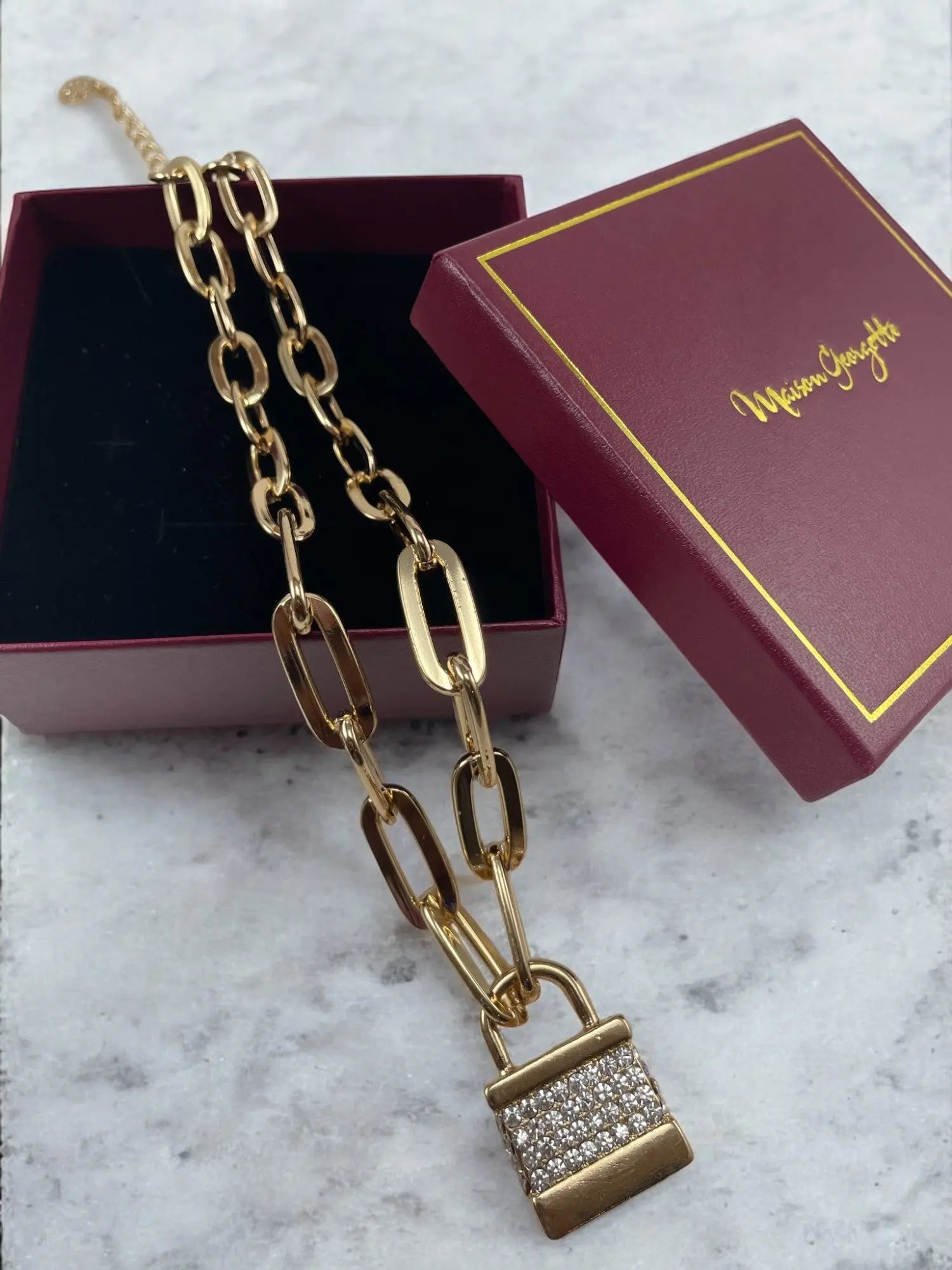 A gold abigail chain lock necklace displayed in a box, representing luxury necklace