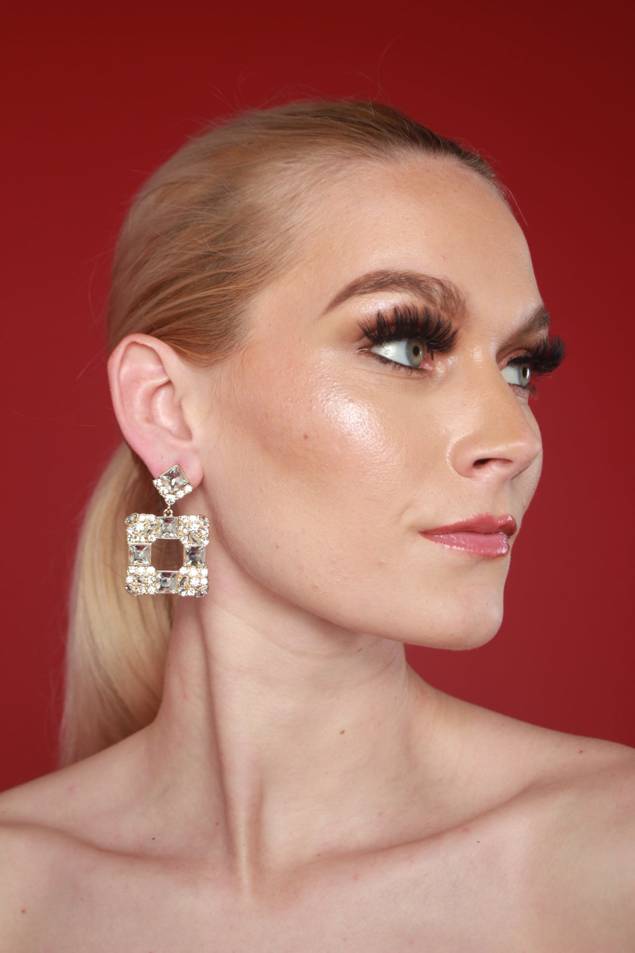 A woman with long blonde hair with Daphne Square Crystal Earrings, exemplifying affordable luxury jewelry