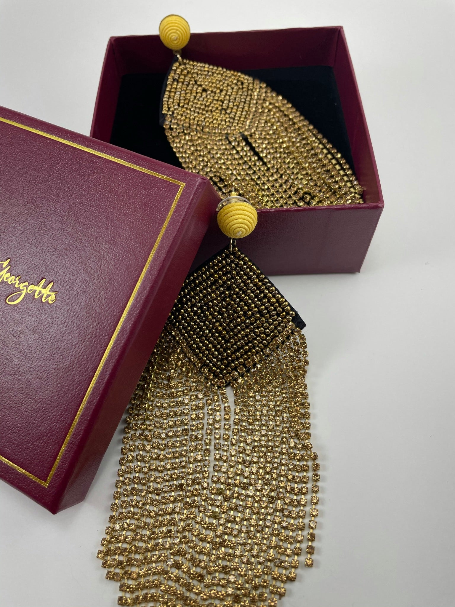 A beautifully crafted pair of gold tassel earrings presented in a box, representing luxury women's earrings