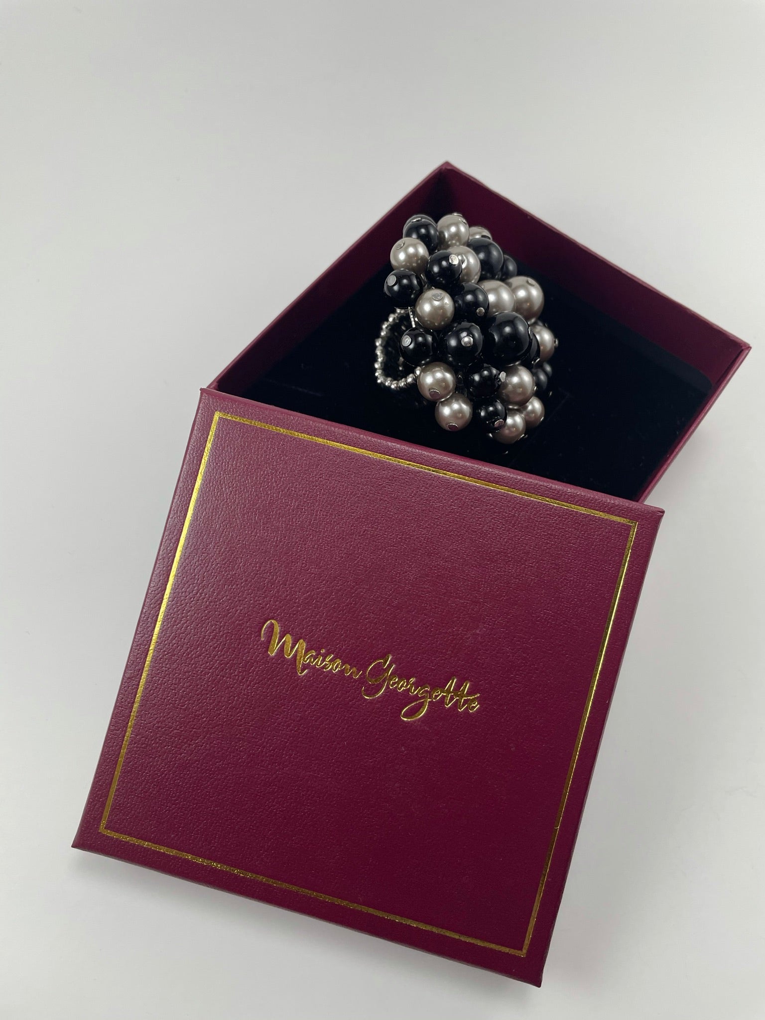 A red box containing a black and white ring, showcasing the elegant Donna Pearl Ring for luxury women's rings